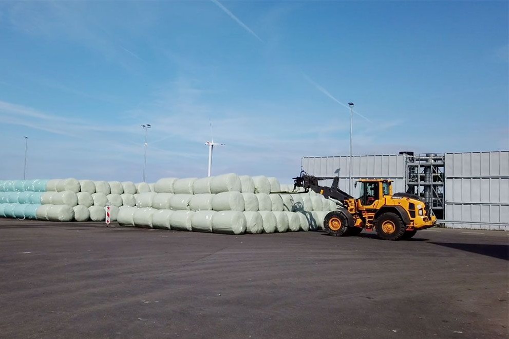 ZAK Radlader bei der Stapellung von weißen Silage-Rundballen im Energiedepot