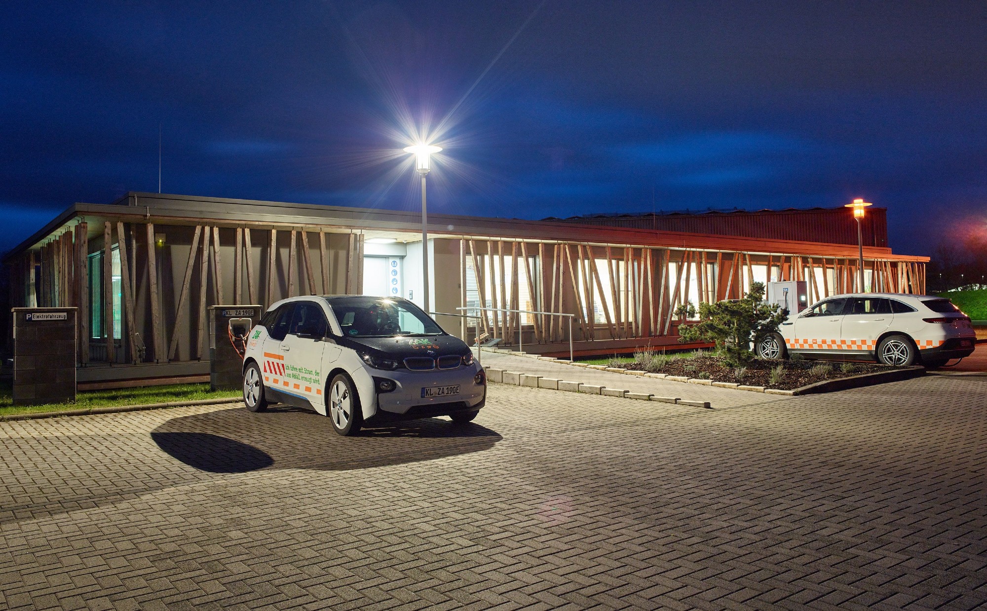 ZAK Haus Aspenkopf bei Nacht mit Beleuchtung und Elektrofahrzeugen zeigt nachhaltiges Gebäudekonzept