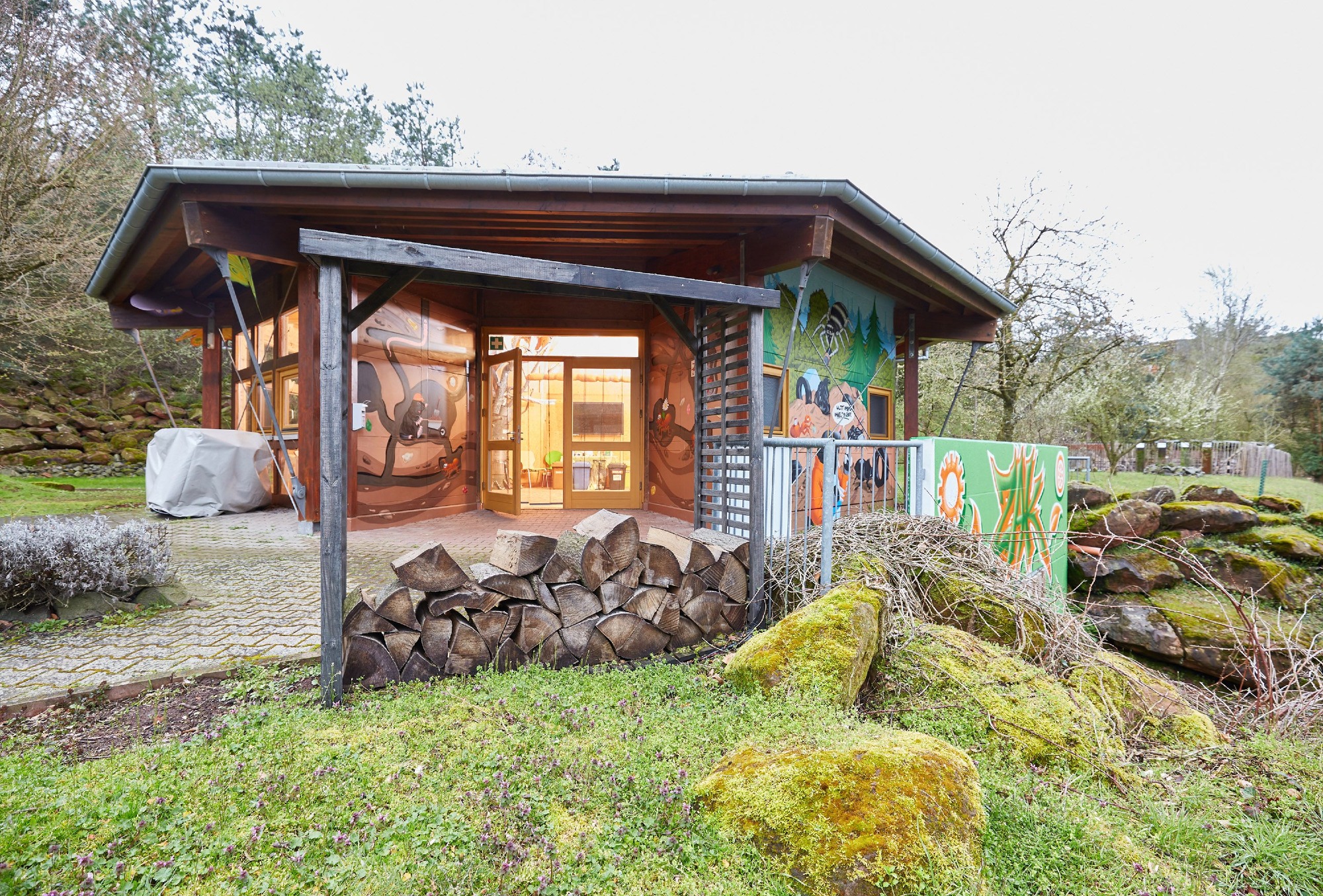 Umwelterlebniszentrum der ZAK: Holzpavillon mit überdachter Terrasse und bunten Informationstafeln zur Umweltpädagogik