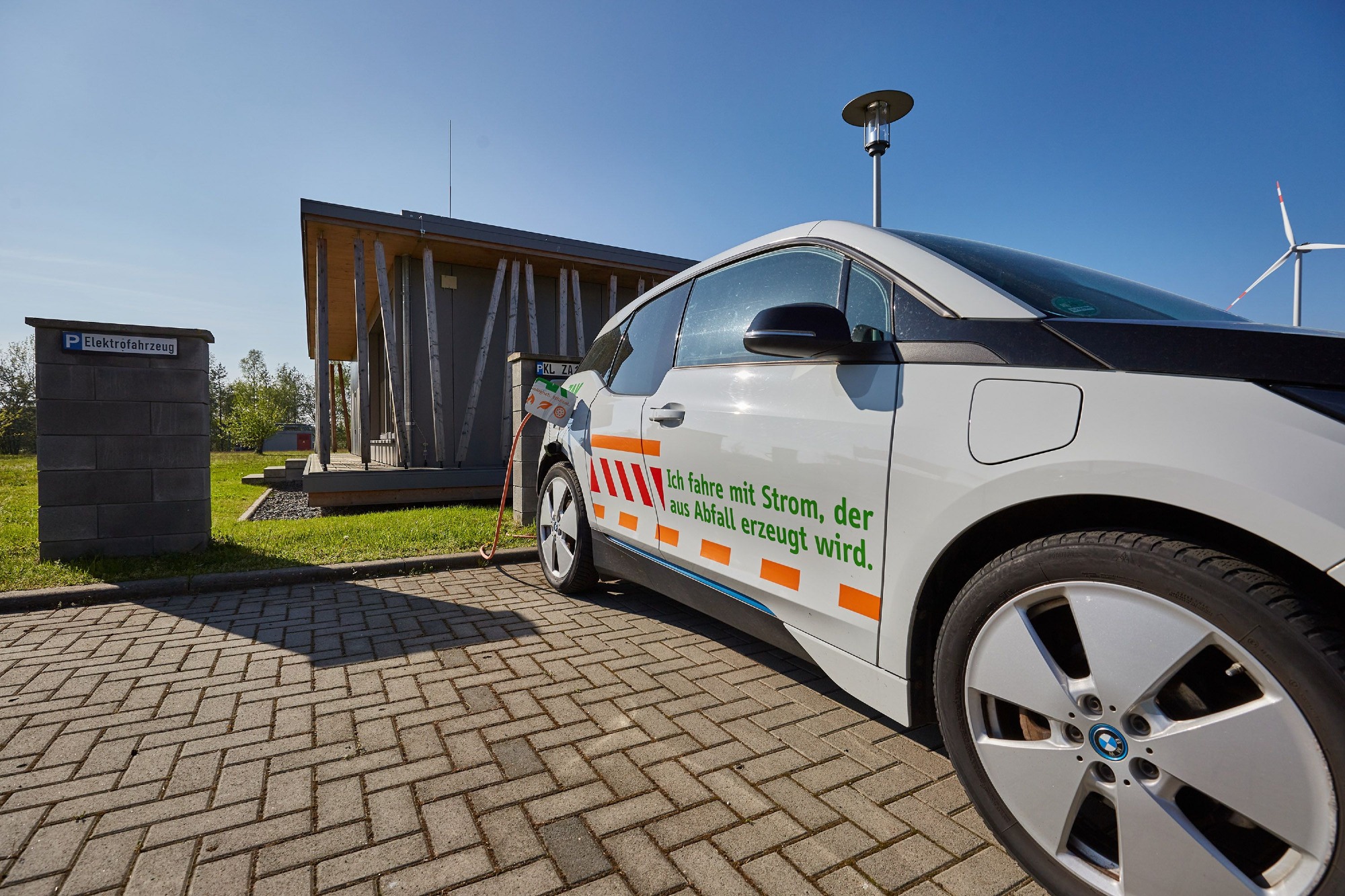 ZAK E-Ladestation mit Elektrofahrzeug vor modernem Holzgebäude zeigt nachhaltige Mobilität am Standort