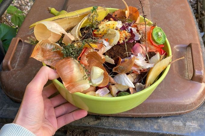 Bioabfall-Sammlung in grüner Schüssel mit Gemüseresten und Küchenabfällen für die Biotonne