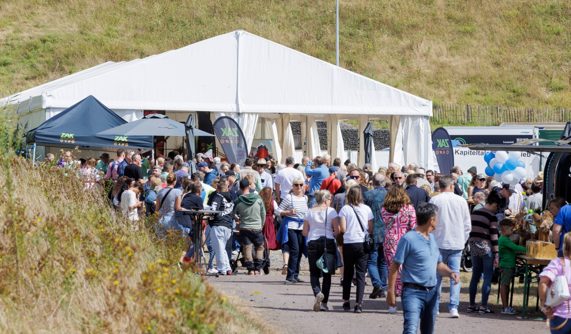 Kapiteltaler Almabtrieb mit großem Besucherandrang vor weißen Festzelten und Ausschankständen auf der Almwiese
