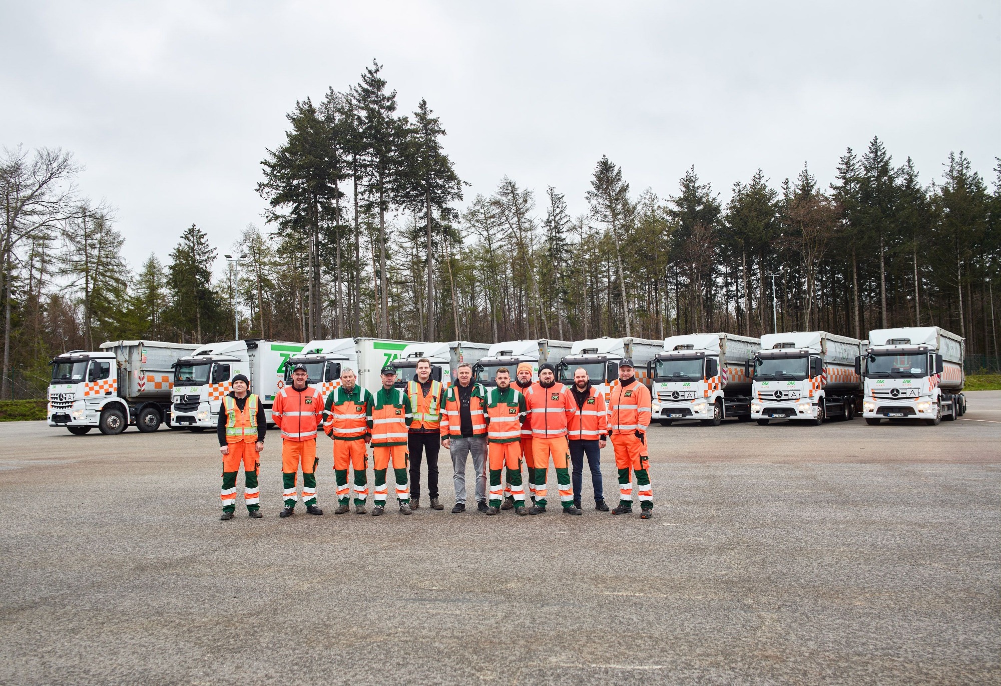 ZAK Fahrerteam in Warnschutzkleidung vor der weißen LKW-Flotte