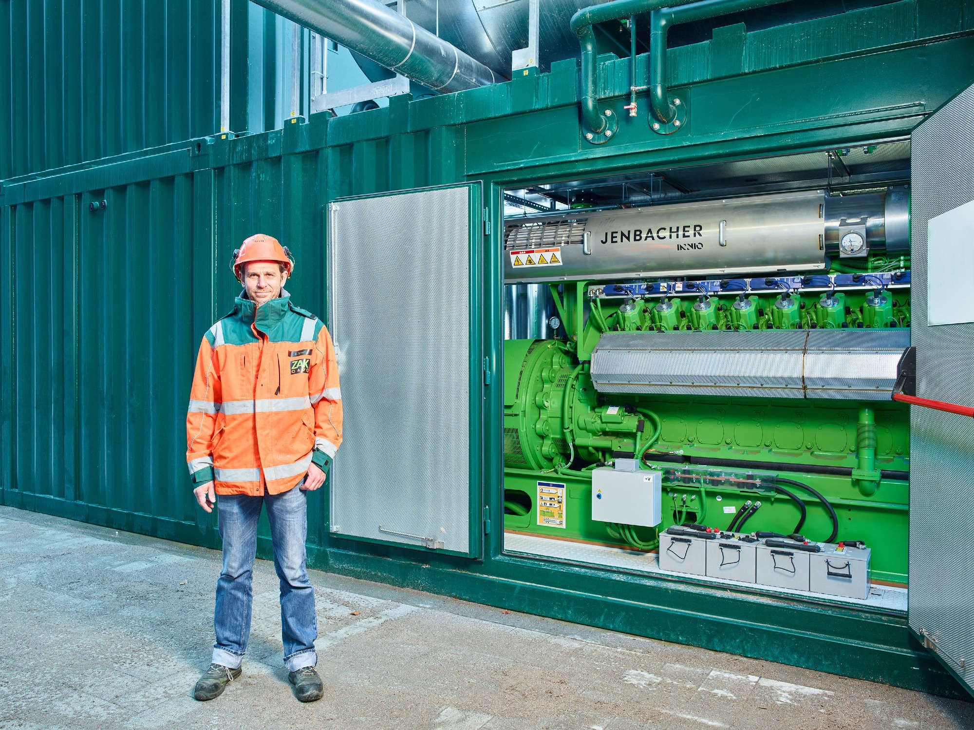 ZAK Gasmotor-Anlage zur Stromerzeugung aus Biogas und Deponiegas mit Mitarbeiter in Schutzkleidung 