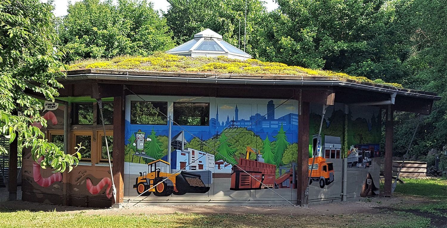 Umwelterlebniszentrum der ZAK: Holzpavillon mit überdachter Terrasse und bunten Informationstafeln zur Umweltpädagogik