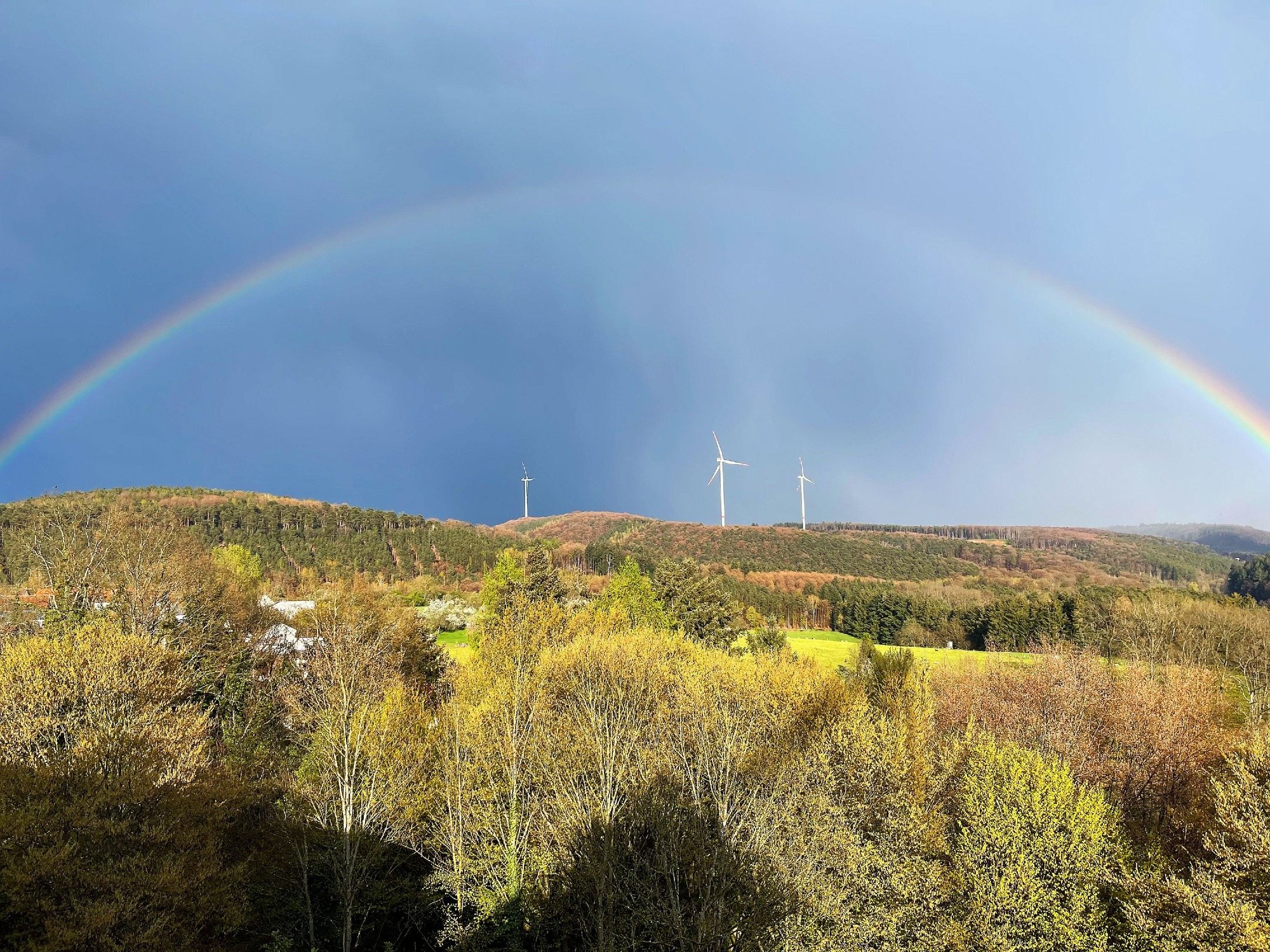 Malerischer Regenbogen über ZAK Deponie-Landschaft mit Windkraftanlage