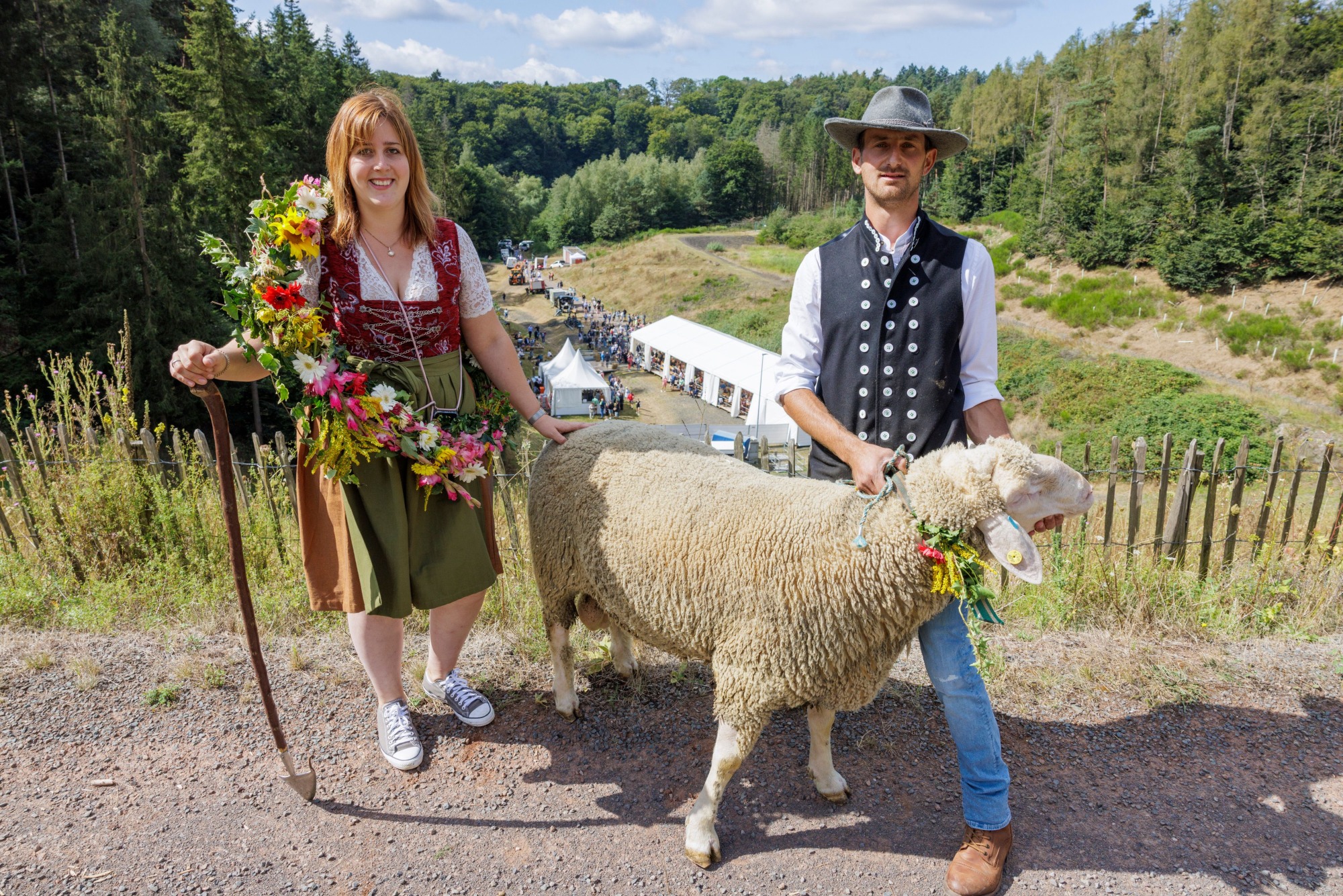Schäfer in Tracht und blumengeschmückten Schafen vor der Festkulisse