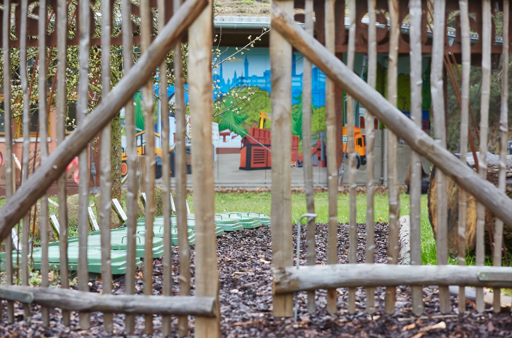 Natürlicher Holzzaun begrenzt Lehrbereich mit bunter Informationstafel im ZAK Freilandklassenzimmer